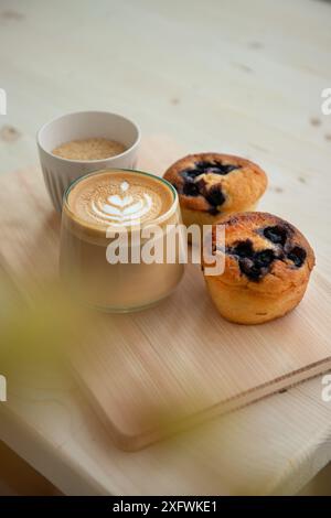 Cappuccino, espresso and blueberry muffins on a coffee shop table. Minimalist style. Selective focus. Stock Photo