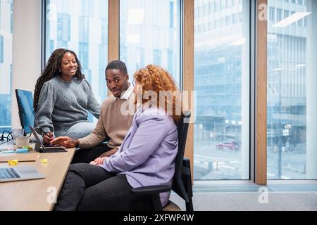 Business colleagues discussing ideas while using laptop in office Stock Photo