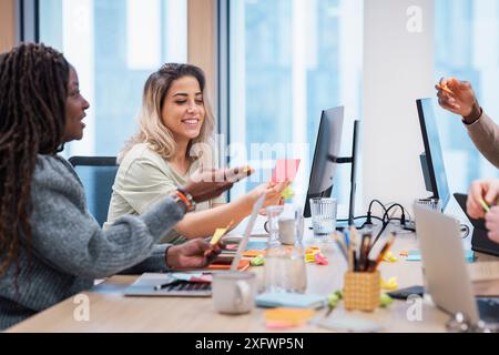 Cheerful young businesswomen discussing strategies with colleagues in office Stock Photo