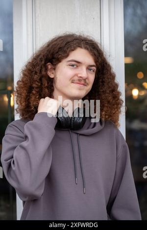 Portrait of young man with long curly hair in front of window Stock Photo
