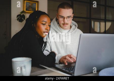 Young male entrepreneur working with female colleague over laptop at home office Stock Photo