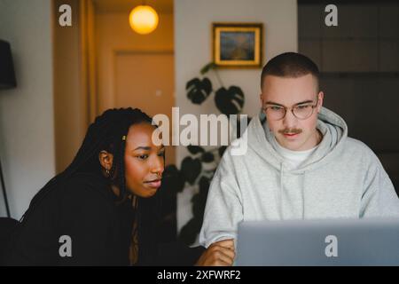 Young male and female entrepreneurs working on laptop at home office Stock Photo