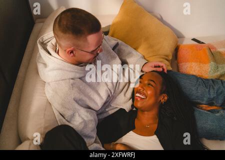 High angle view of happy woman lying down on boyfriend's lap at home Stock Photo