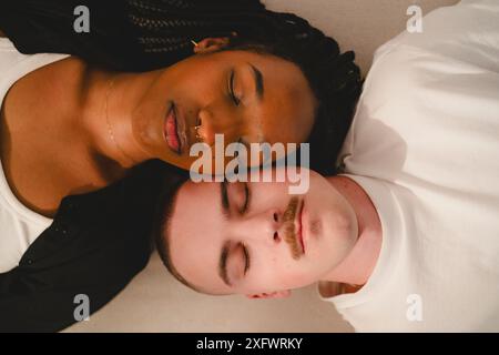 Young multiracial couple sleeping while lying next to each other at home Stock Photo
