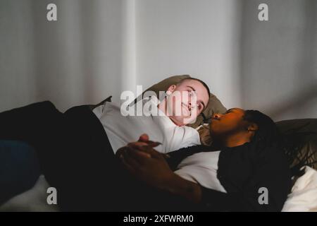 Young man lying down with girlfriend on bed at home Stock Photo