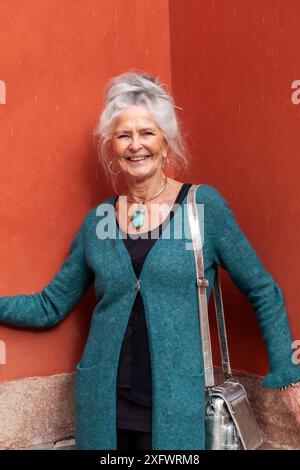 Portrait of cheerful senior woman standing in front of wall Stock Photo