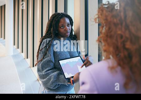 Young businesswoman explaining graph to colleague in office Stock Photo