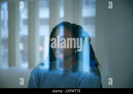 Thoughtful businesswoman seen through glass window in office Stock Photo