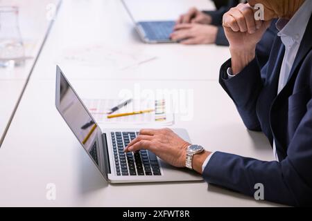 Midsection of senior businessman using laptop at table in office Stock Photo