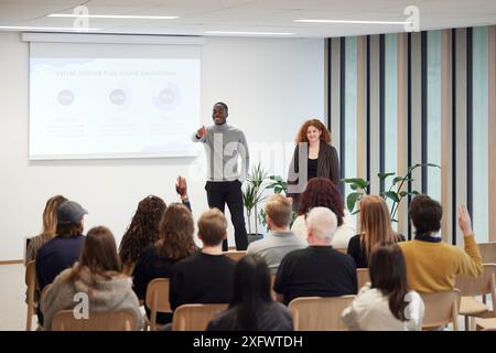 Multiracial colleagues giving presentation to employees in office Stock Photo