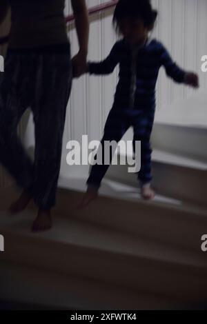 Low section of mother with daughter moving down on stairs at home Stock Photo