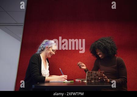 Young businesswomen making notes during discussion in office Stock Photo