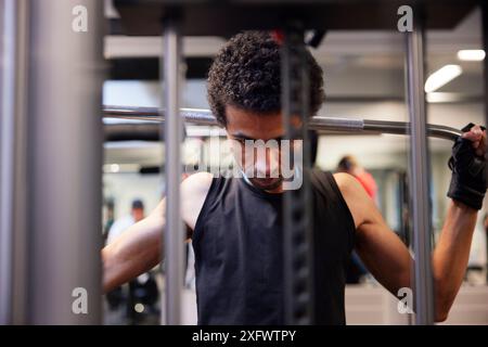 Focused young man doing lateral pull-down weightlifting at gym Stock Photo