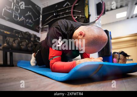Surface level of bald man doing plank on exercise mat at gym Stock Photo