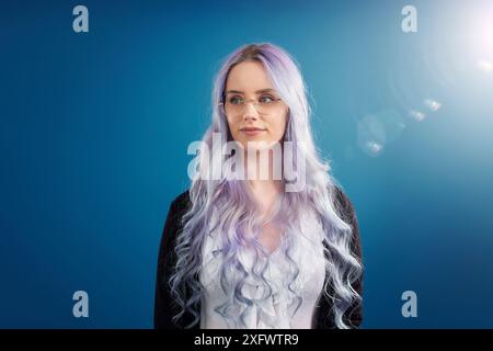 Beautiful young businesswoman standing against illuminated blue background Stock Photo