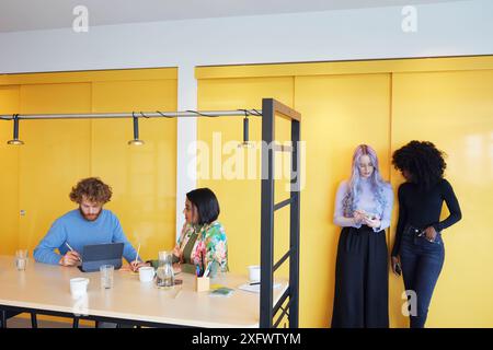 Multiracial corporate colleagues using phone and digital tablet during discussing in office Stock Photo