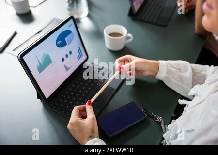 Midsection of businesswoman analyzing graph on digital tablet in office Stock Photo