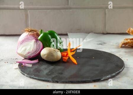 Empty black circular plate with vegetables on the side for food product placement. Stock Photo