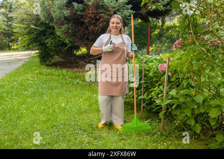 Raking leaves. Female is raking leaves with a rake. Picture of woman working with tools in the garden Stock Photo