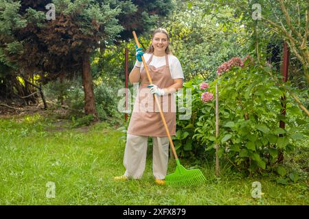 Raking leaves. Female is raking leaves with a rake. Picture of woman working with tools in the garden Stock Photo
