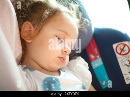 Cute blond baby sleeping in baby car seat. Safety Concept. Stock Photo