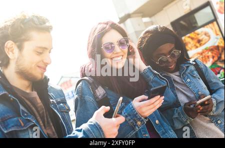 Multiracial friends having fun with smartphone in a spring day. Stock Photo
