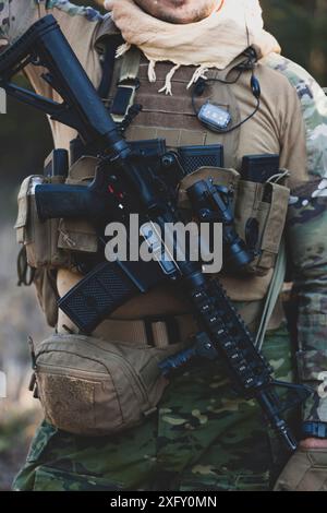 Airsoft military game player in camouflage uniform with armed assault rifle. Stock Photo