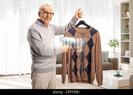 Elderly man using a hand steam iron at home in a living room Stock Photo