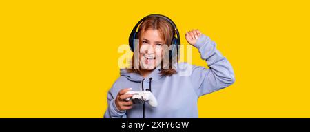 teenage girl celebrates a victory playing video games. yellow background Stock Photo