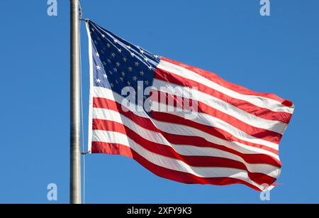 american flag waving in breeze against blue sky Stock Photo