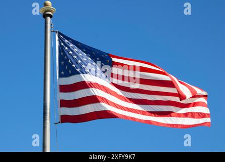 american flag waving in breeze against blue sky Stock Photo