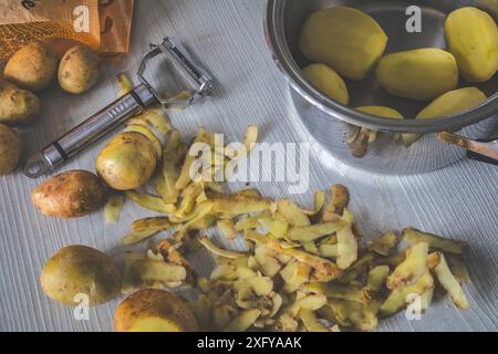 preparation phase of a potato-based recipe, peel the potatoes with the appropriate tool, potato peeler Stock Photo
