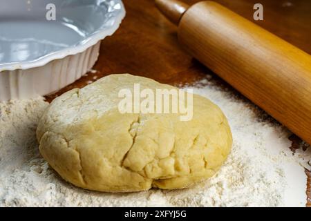 Making a pie.  Getting ready to make a pie.  Dough on a floured wooden surface.  Pie plate and wooden rolling pin in background. Stock Photo