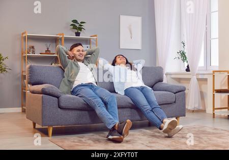 Happy, smiling, young family couple relaxing on a comfortable gray couch at home Stock Photo
