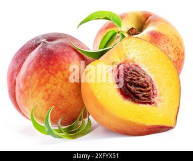 Ripe juicy peach half and two peaches with green leaves isolated on white background. Stock Photo