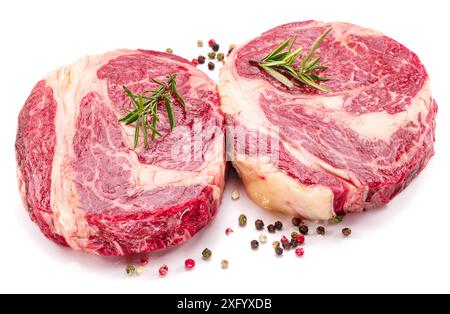 Raw beef steaks with herbs and spices ready for cooking on white background. Stock Photo