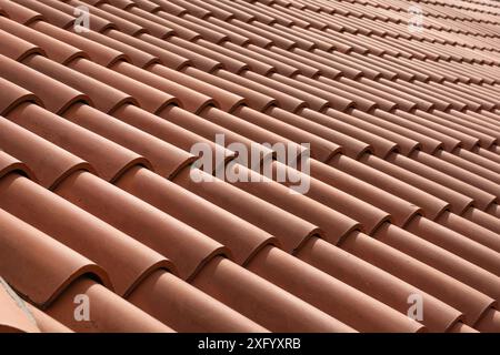 Red corrugated roof tile element on a house on a sunny day. Shingles roofing surface tiles overlay pattern and texture. Stock Photo