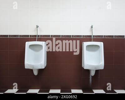 White urinals in the men's bathroom with tiled wall. Stock Photo