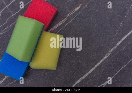 Four different colored scouring pads on a dark marble surface Stock Photo