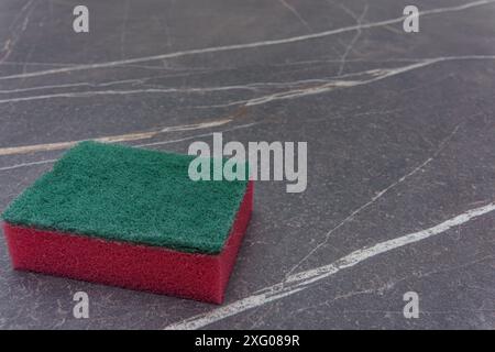 A red cleaning sponge on a marble table top Stock Photo