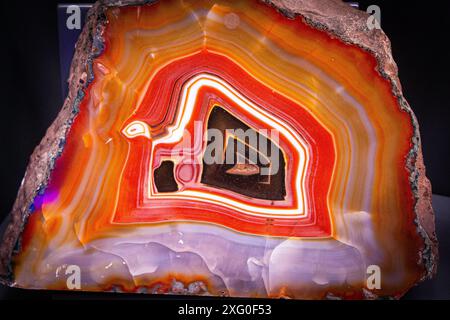 Chalcedony agate abstract orange, red and black background with waves. Agate stone wallpaper. Polished gemstone texture colors gradient Stock Photo