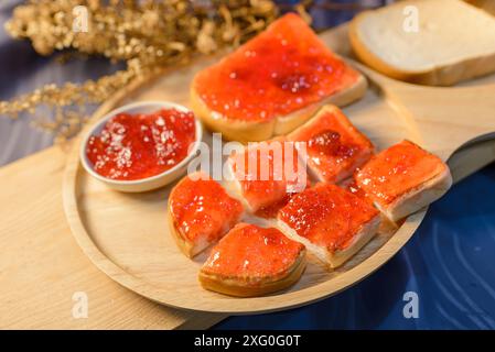Slices of bread with strawberry jam on a wooden board. . Stock Photo