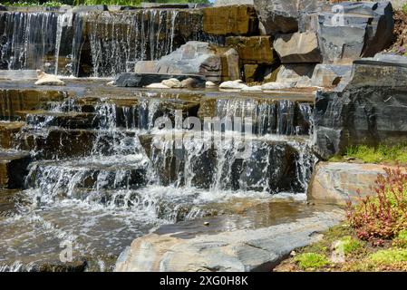 Close-up of water flowing down large stones in the cascading waterfall. Walking through the park. Stock Photo