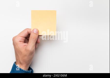 A man's hand is holding a yellow sticker. Writing notes, daily plans and reminders. Place for text Stock Photo