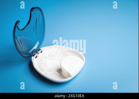 Orthodontic care, new invisible plastic aligners printed on a 3d printer lie in a special white box, on a blue background without people Stock Photo