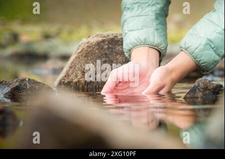 Close-up of a girl's hands and water from a mountain lake, nature, a clean source of water to quench thirst Stock Photo