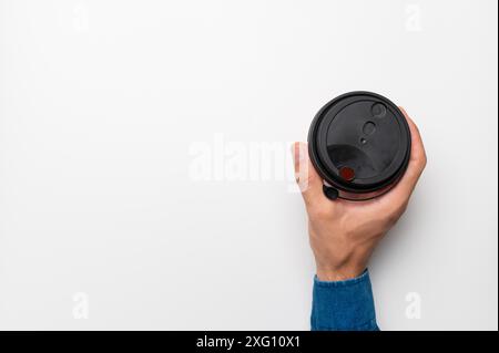 Male hand holding takeaway coffee cup with americano on white background and top view, with blank ad space on side Stock Photo