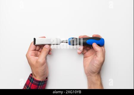 Carpenter's hands Close-up of a man's hands in a plaid shirt on a white background with a chisel, studio shot Stock Photo