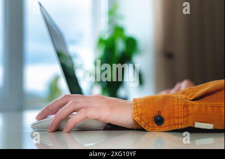 Home environment, woman's hand rests on laptop mouse, work from home Stock Photo