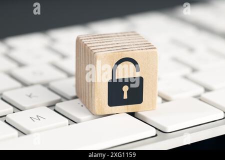 Computer security risk concept. Open padlock icon on wooden cube on computer keyboard Stock Photo